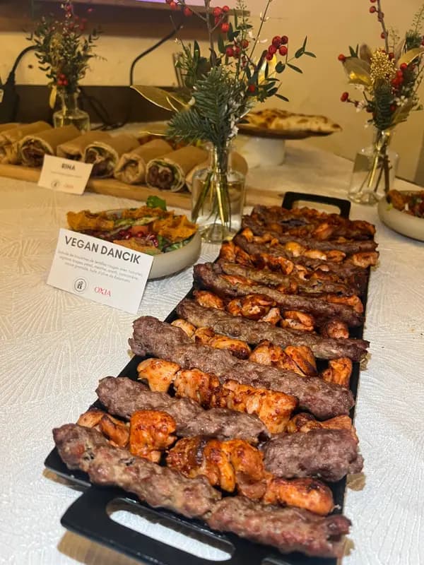 Grilled meat skewers and chicken kebabs on a buffet table with vegan options and festive floral decor